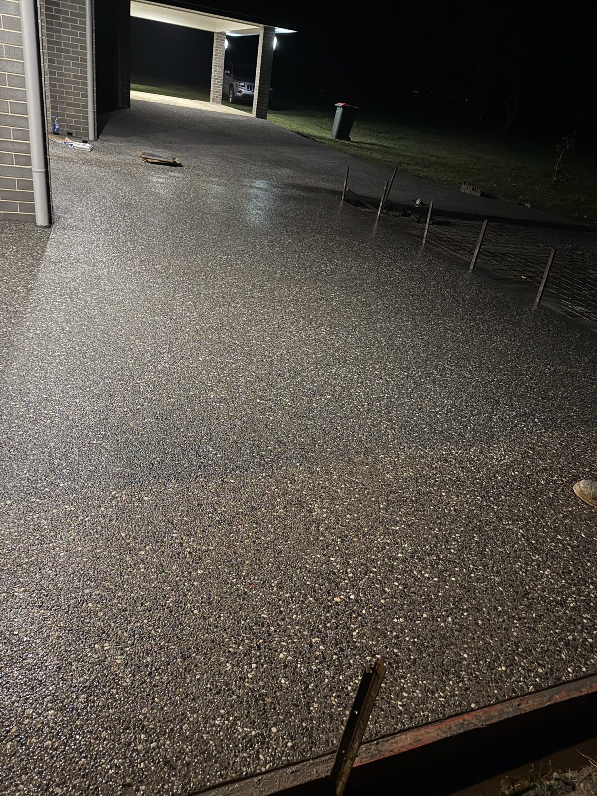 Sealed exposed aggregate concrete driveway lit at night by EAB Concreting, Hunter Valley